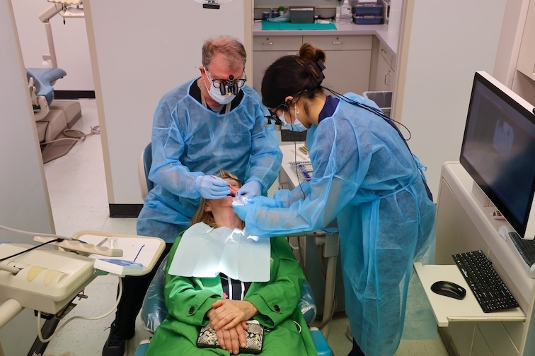 Dentist mentors student while working with a patient.