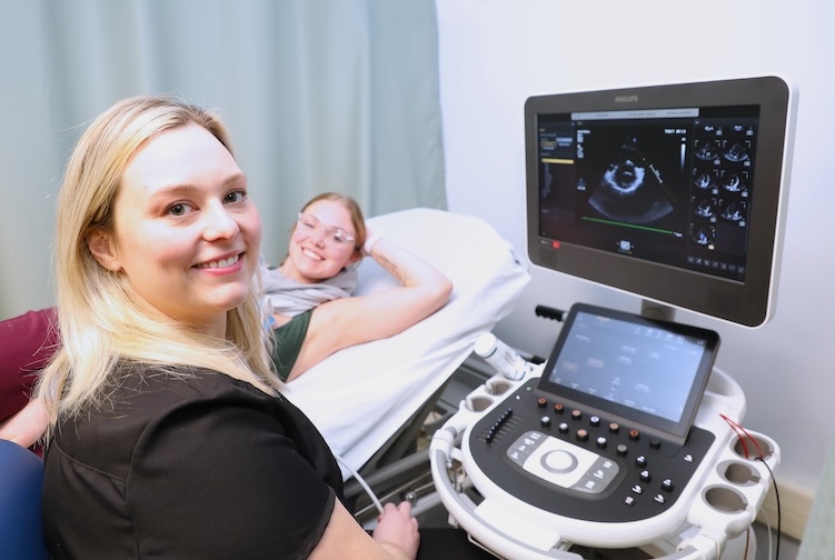  two students smile while practicing a echocardiogram
