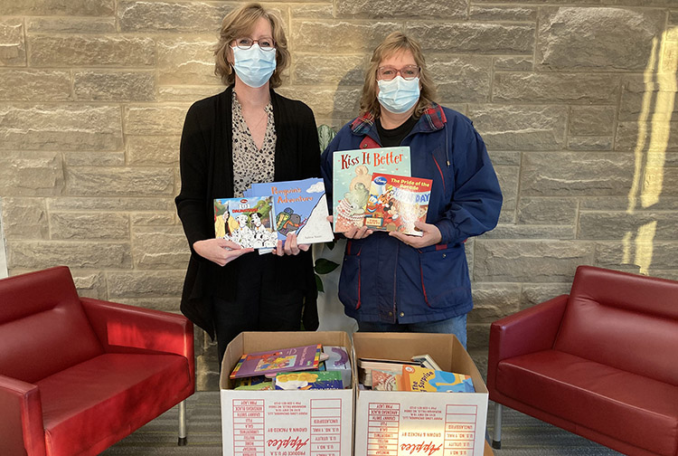 two ladies donate two boxes of books to a hospital