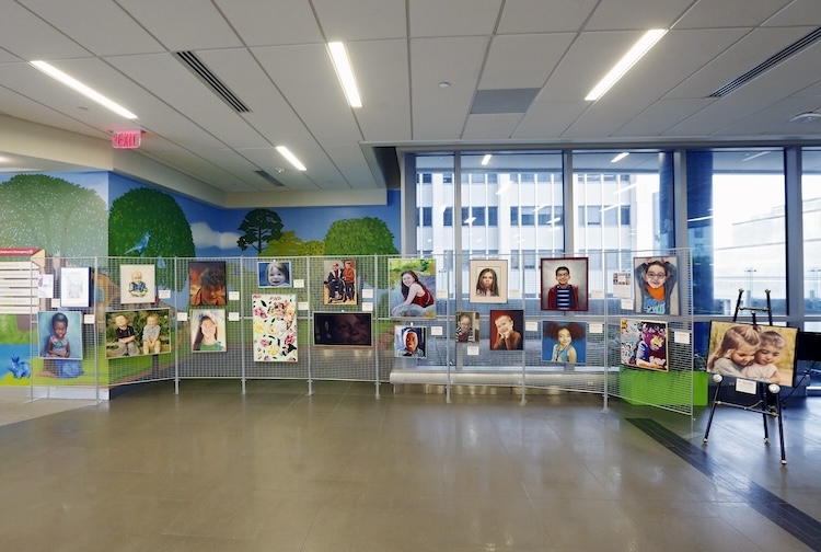 paintings of pediatric patients line a hallway