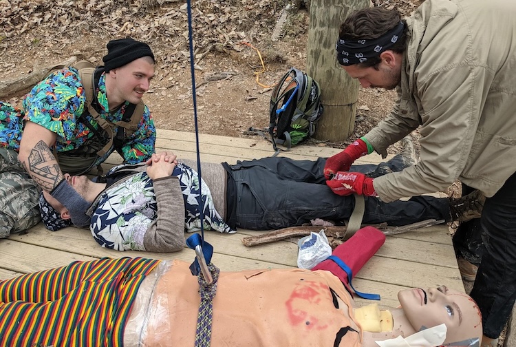 two men practicing emergency medicine on a dummy and a person.