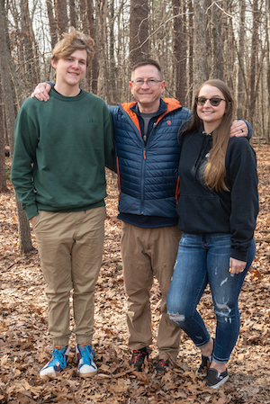 Greg Leitz with his son and daughter standing outside on fall leaves