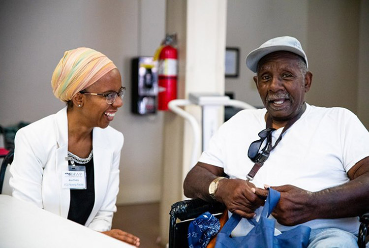 a female nurse laughs with an elder male patient
