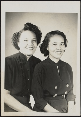 Two women pose together for a photo, the are sisters and are smiling. 