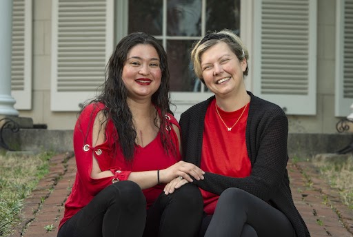 Two women sitting, smiling, and holding hands on steps