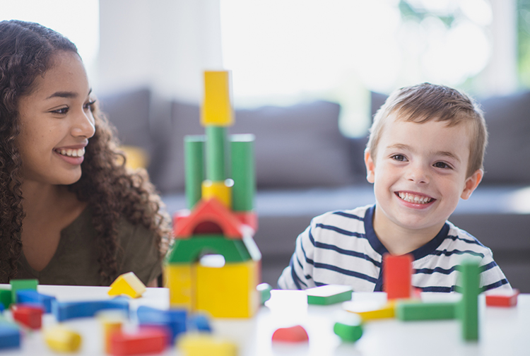 Woman and child smiling and playing with blocks
