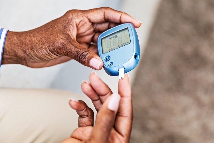 Image of person performing finger prick test with a blood glucose monitor