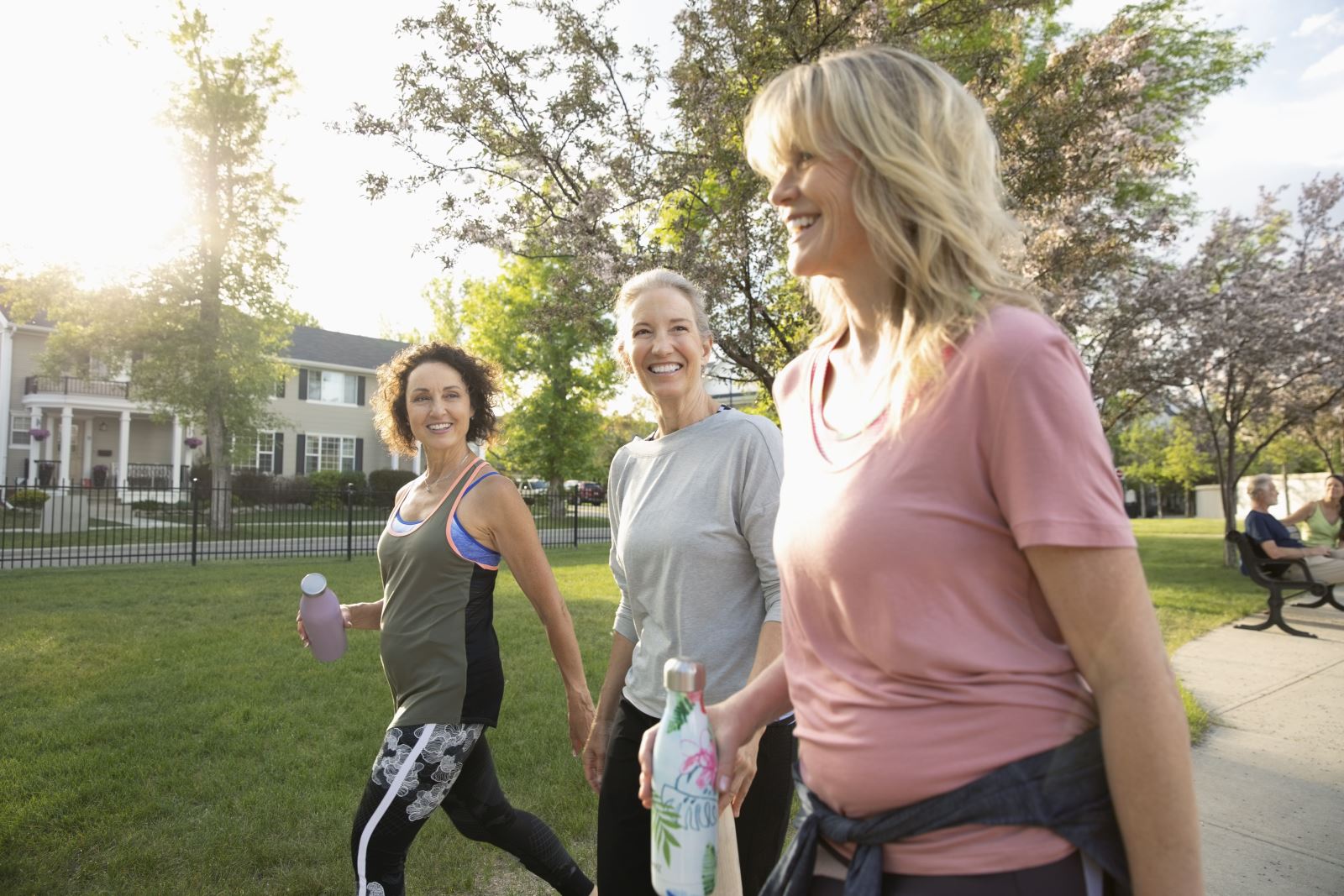 Three smiling woman walking in a neighborhood.
