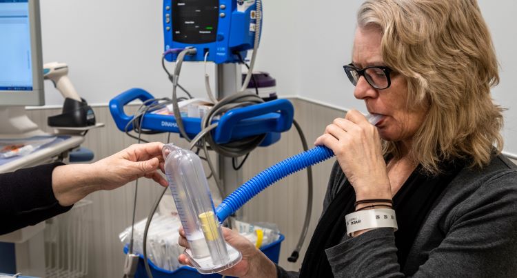 Patient blows into spirometer to assess her lung function